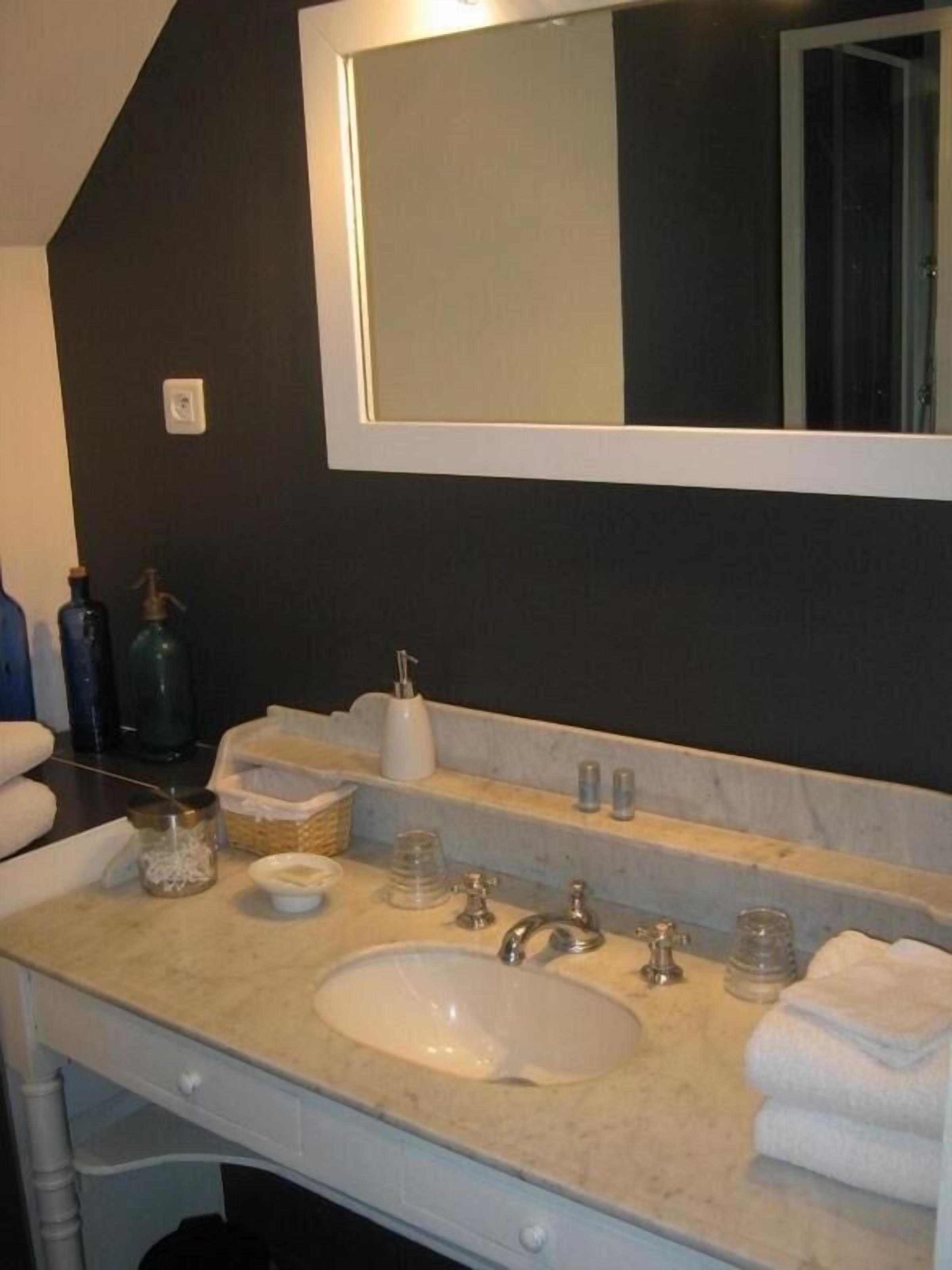 A bathroom with a large mirror, two sinks, and various toiletries.