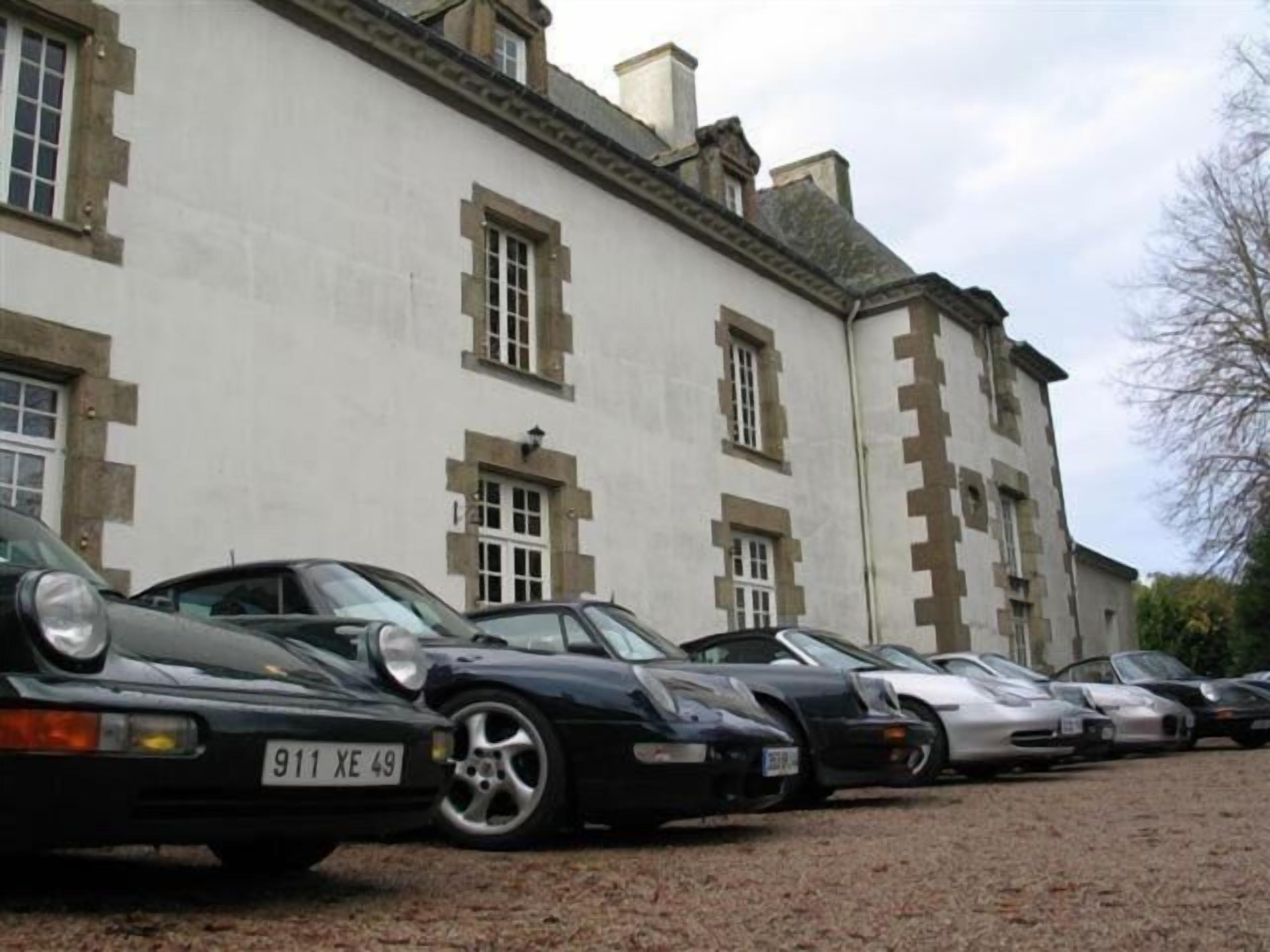 Une rangée de voitures garées devant un immeuble au style architectural classique, caractérisé par des fenêtres symétriques et une façade en pierre.