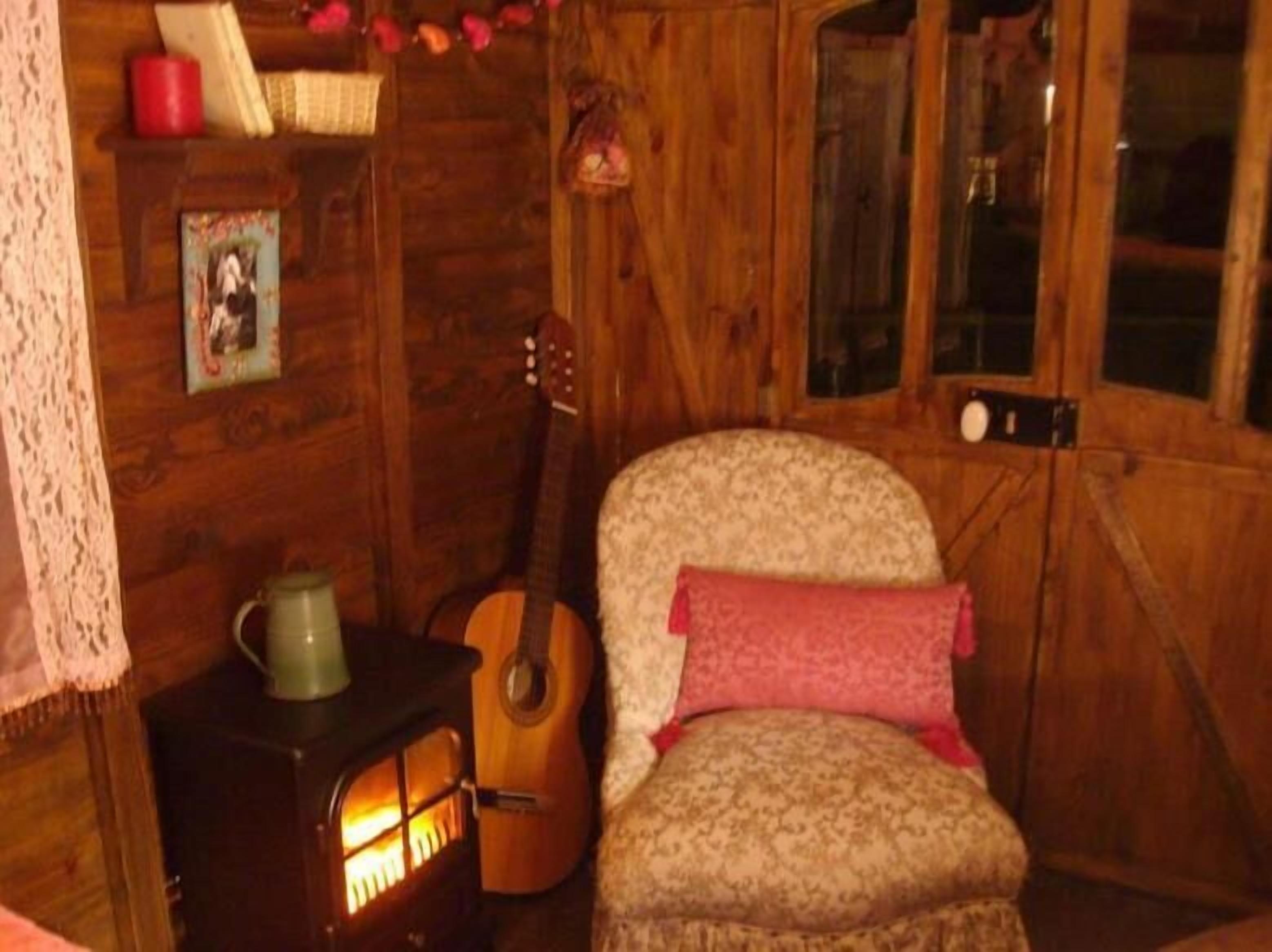 Una habitación acogedora con paredes de madera, chimenea, una guitarra y un sillón estampado.