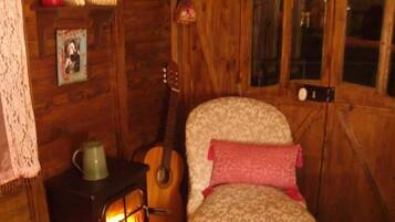 Una habitación acogedora con paredes de madera, chimenea, una guitarra y un sillón estampado.