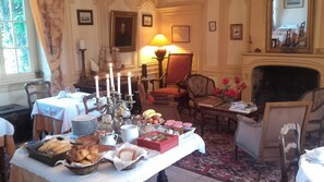Un comedor con una mesa preparada para una comida, que incluye pan, pasteles y un centro de mesa con una vela.