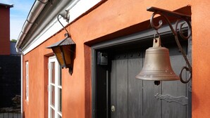 Een gebouw met een houten deur en een aan de muur bevestigde bel.