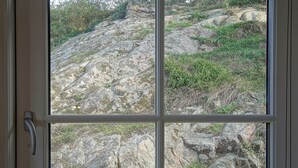 Een raam met een zicht over een ruig landschap.