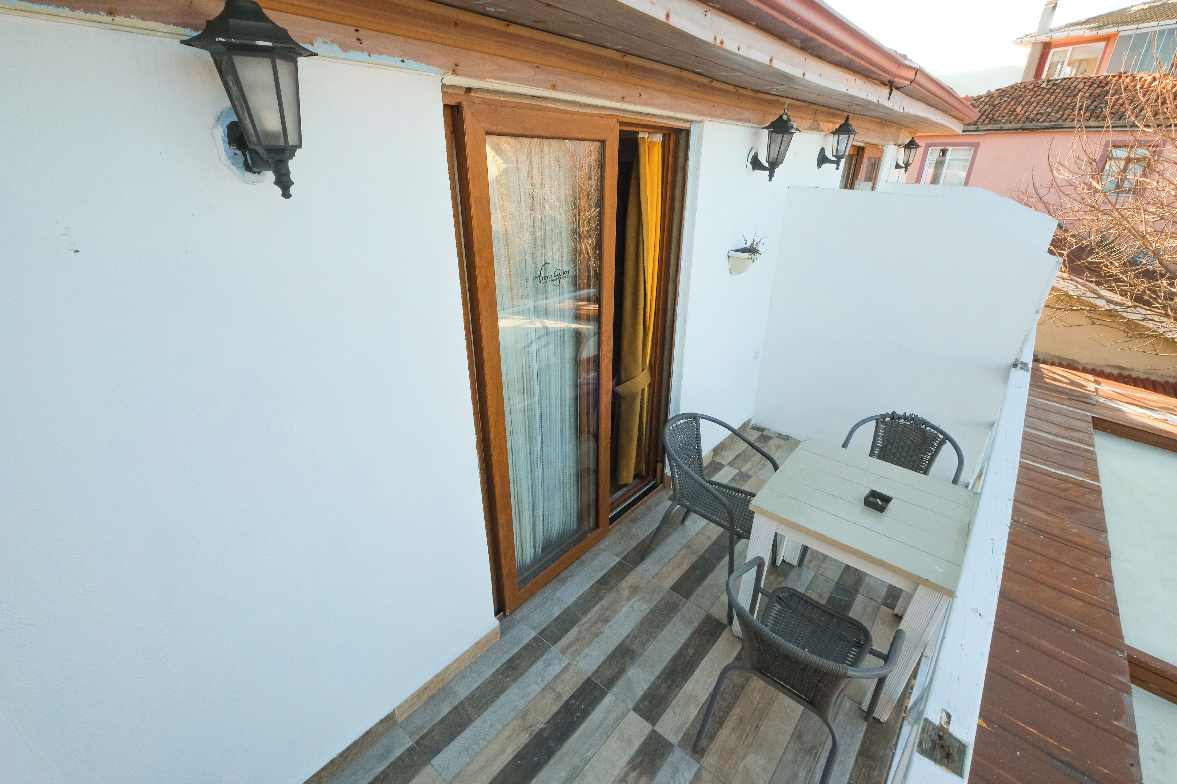 Ein Balkon mit Tisch, Stühlen, einer Schiebetür und einem Holzboden.