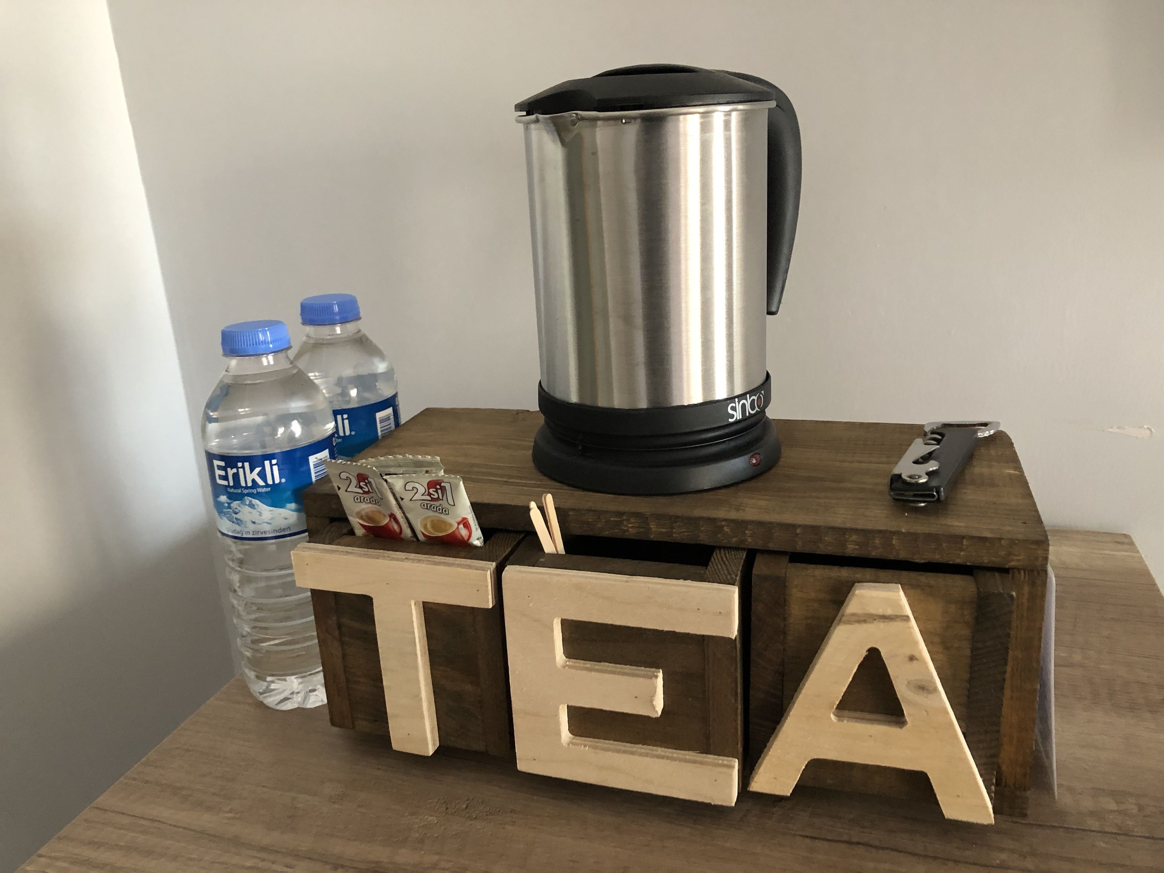 A wooden block with the word "TEA" and two water bottles labeled "Erikli" on a table.