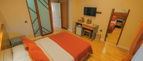 A hotel room with a bed, a desk, a TV, and a mirror.