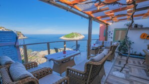 Un patio al aire libre con mobiliario de mimbre, una mesa y vista al mar.
