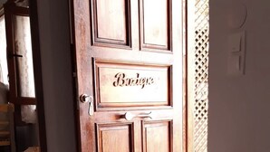 Una puerta de madera con el nombre "Bourgogne" grabado, una pequeña mesa de madera y un muro con celosía.
