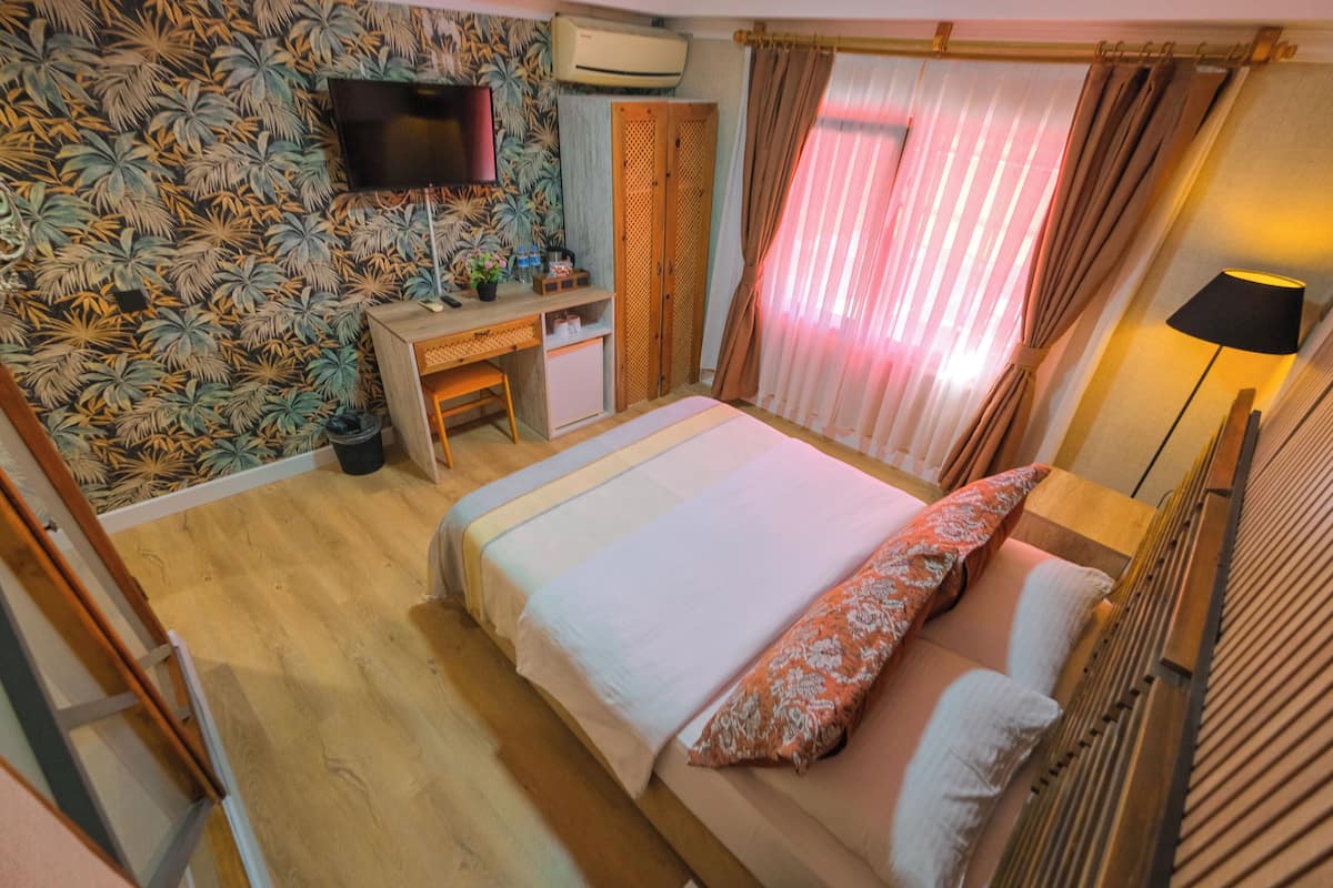 A room with a bed, a desk, a TV, and a wardrobe.