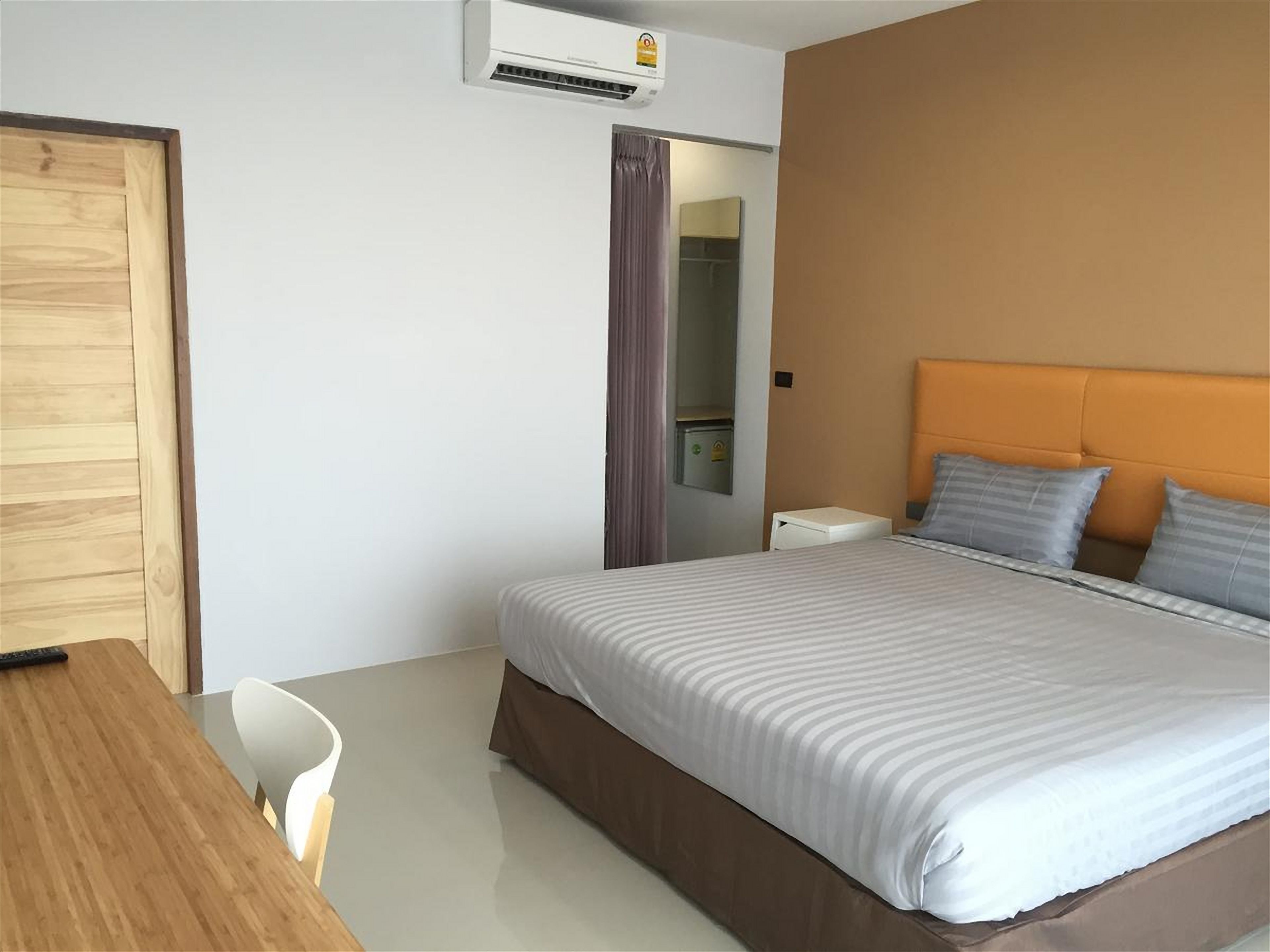 Une chambre d’hôtel avec un lit, un bureau en bois, une chaise et une armoire.