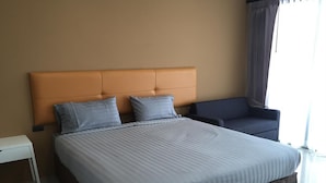 A modern hotel room with a large bed, a headboard, a bedside table, and a chair. - The Lofts Eco (Sung Noen)