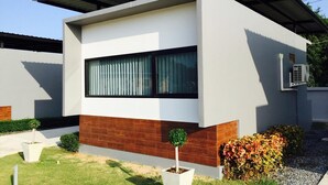 A modern two-story house with a flat roof, large windows, and a brick base. - The Lofts Eco (Sung Noen)