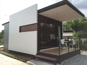 Un edificio moderno y compacto con acceso de vidrio y un pequeño espacio al aire libre para sentarse.