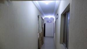 A narrow hallway with white walls, a tiled floor, a window on the right, and a door at the end. - Royal Green Guest House (Abeokuta)