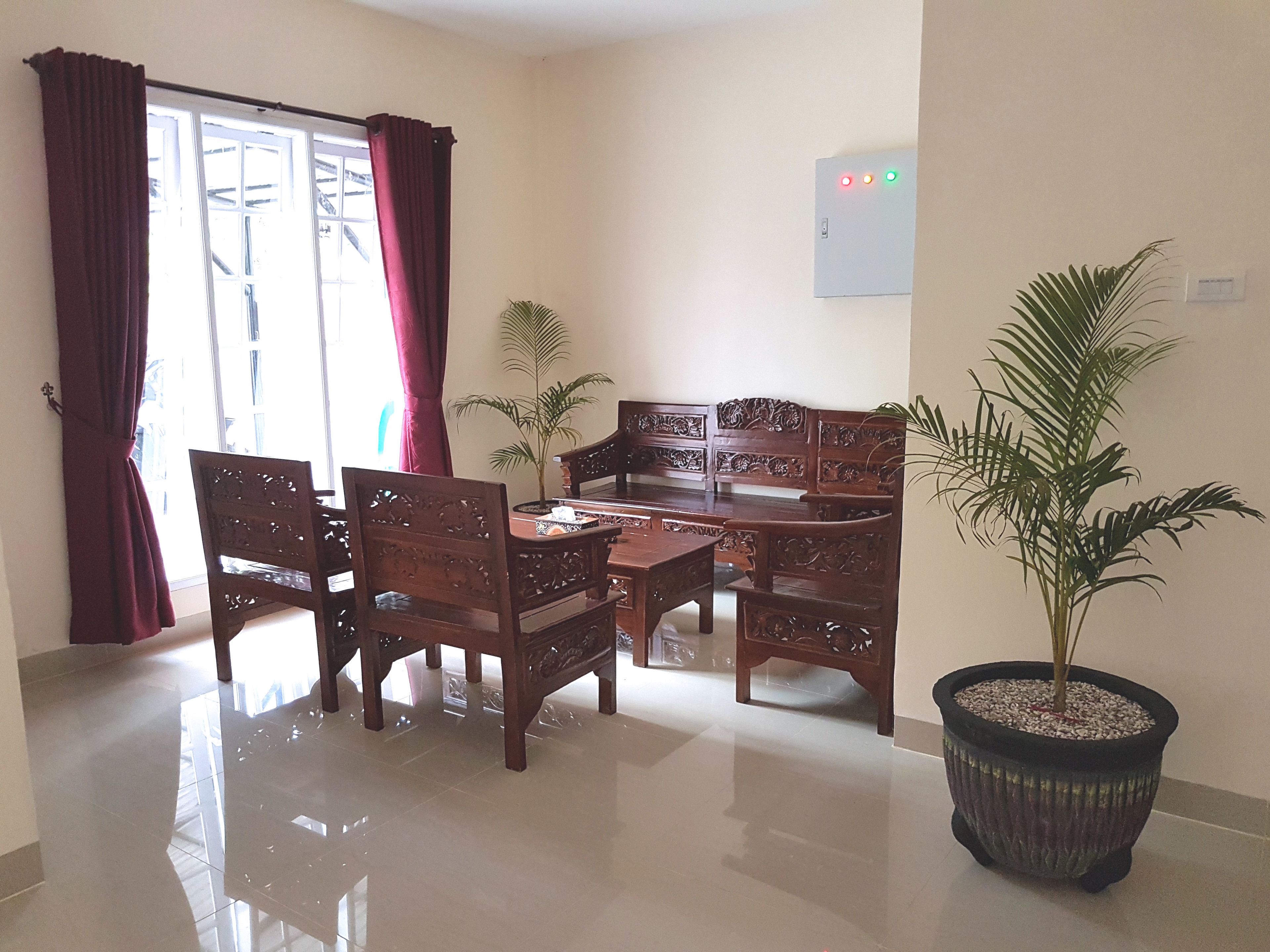 Uma área de refeições com mesa e cadeiras de madeira, um vaso com planta e um interruptor de luz fixado na parede.
