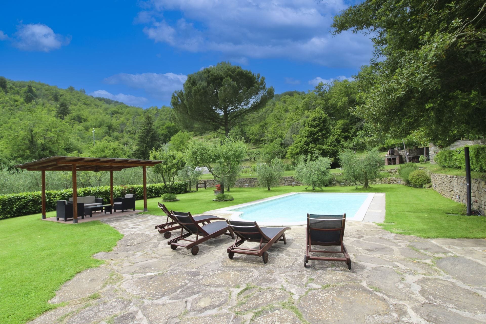 Area piscina con lettini e un gazebo.