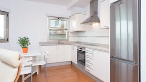 A modern kitchen with white cabinetry, a stainless steel refrigerator, and a built-in oven. - Nice frontline apartment in Playa de Arinaga (Arinaga)