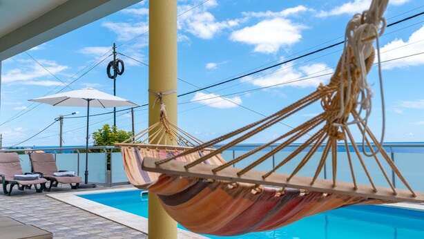 Uma rede perto de uma piscina, com cadeiras de descanso e guarda-sóis.