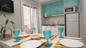 A modern kitchen with teal cabinets, a white refrigerator, and a dining area set with white plates, blue glassware, and a striped placemat. - Ferhouse Dreams- Farilhões (Nazaré)