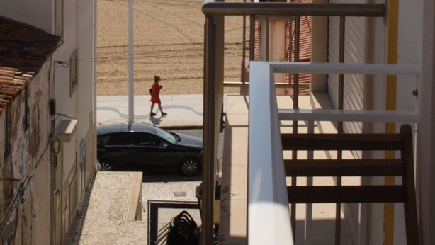 A balcony overlooking a beach with a pedestrian and a car in the foreground. - Ferhouse Dreams- Farilhões (Nazaré)