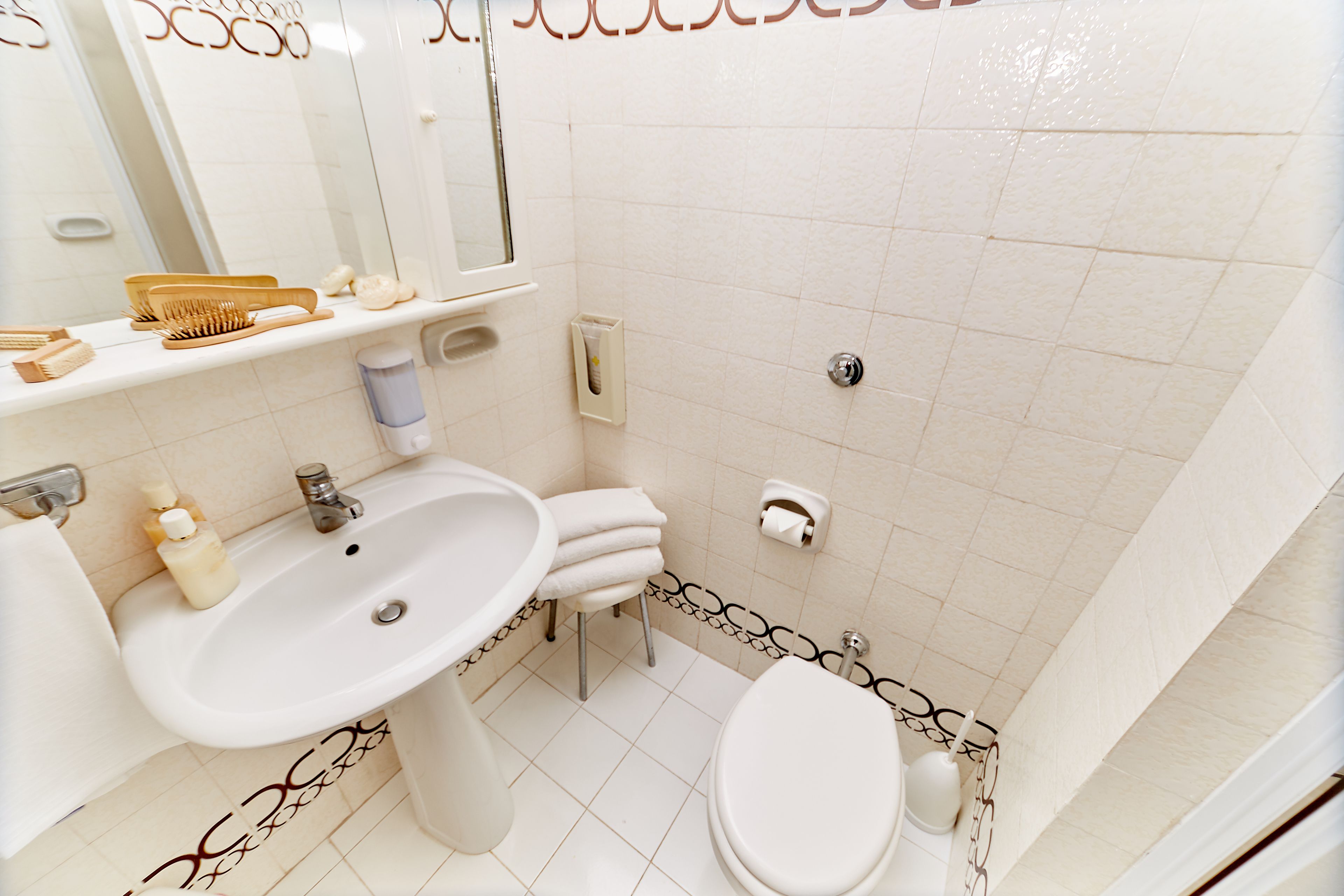 A bathroom with a sink, toilet, and mirror.