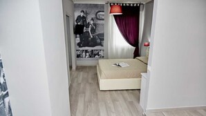 Un dormitorio con una cama, una lámpara roja y una pared con fotografías blanco y negro.