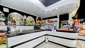 Un bar moderno con una barra curvada, estantes llenos de diferentes bebidas y un reloj visible en la pared.