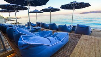 Une terrasse avec des poufs bleus et des parasols, offrant une vue sur la mer.