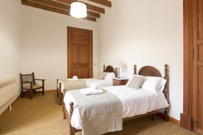 Ein Schlafzimmer mit zwei Holzbetten, einem Holzstuhl, einem Heizkörper und einer Holztür.