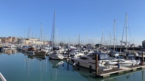 Un puerto deportivo con numerosas embarcaciones amarradas, agua tranquila y edificios al fondo.