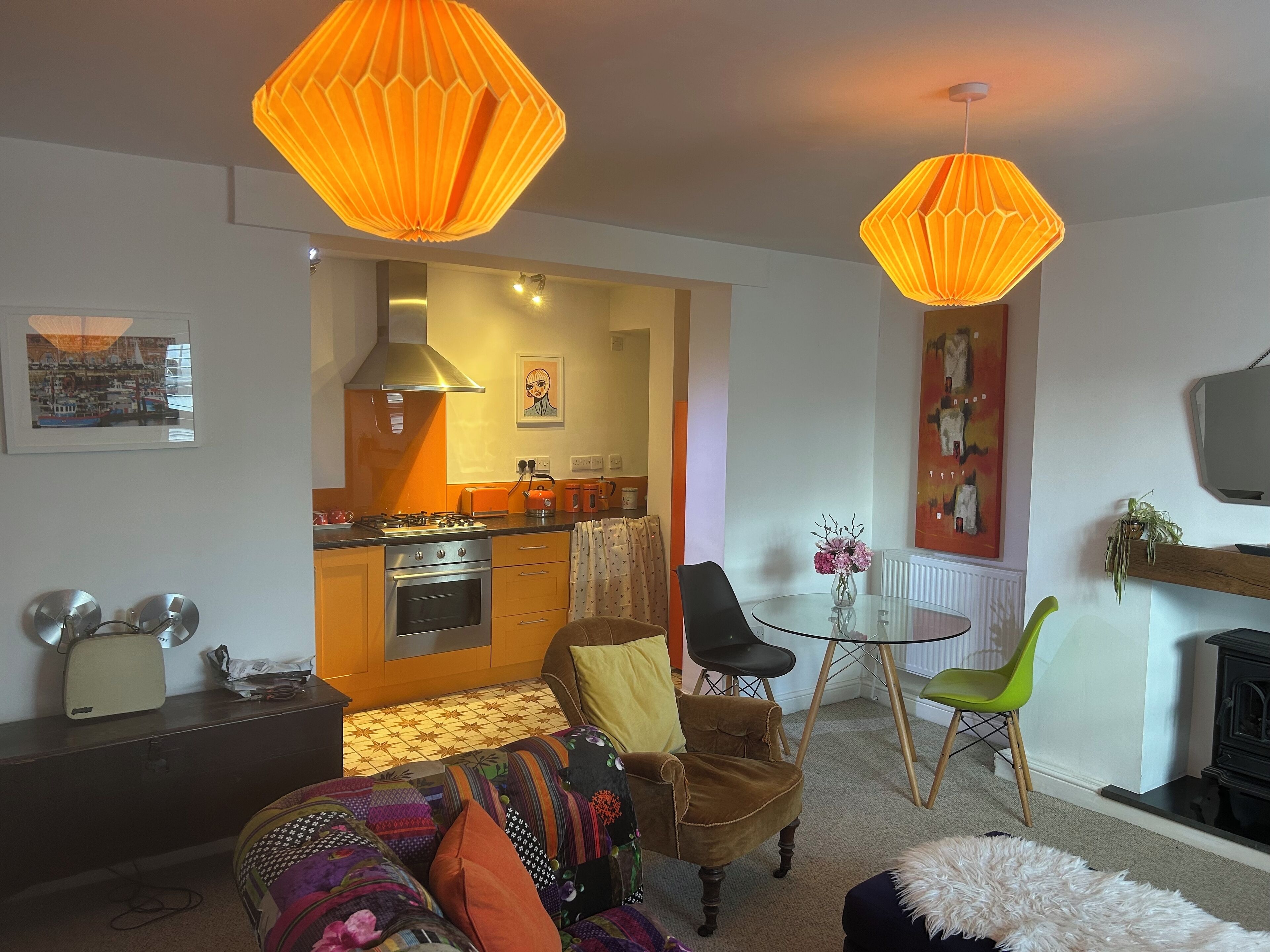 Una sala de estar acogedora con un sofá, una mesa de centro y un televisor. Se observa una cocina al fondo con estufa y armarios.