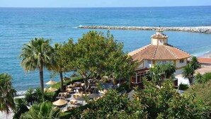 A coastal resort with a dining area, palm trees, and a view of the sea. - Beachside villa with panoramic sea views (Benalm���dena-Costa)