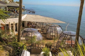 A resort with glass-domed structures overlooking a beach and the sea.