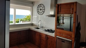 Una cocina con vistas al mar, un reloj y electrodomésticos modernos.