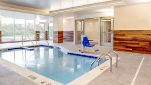 An indoor swimming pool with clear water, a blue chair, and a wooden wall. - Fairfield Inn & Suites Kenosha Pleasant Prairie (Pleasant Prairie)