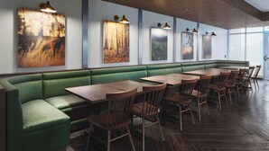 A restaurant with a green booth seating area, wooden tables, and chairs. - Fairfield Inn & Suites Kenosha Pleasant Prairie (Pleasant Prairie)