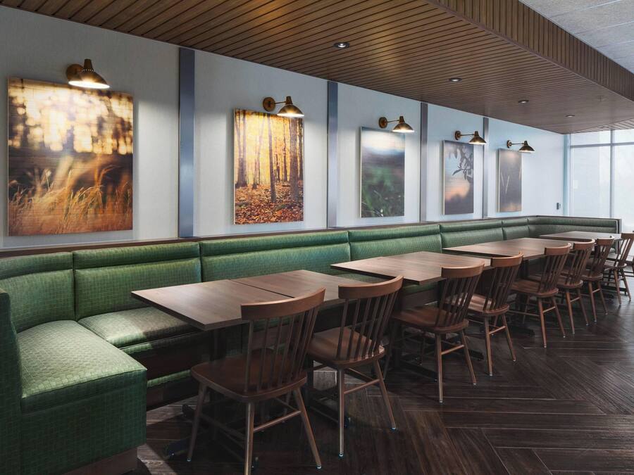 A restaurant with a green booth seating area, wooden tables, and chairs.