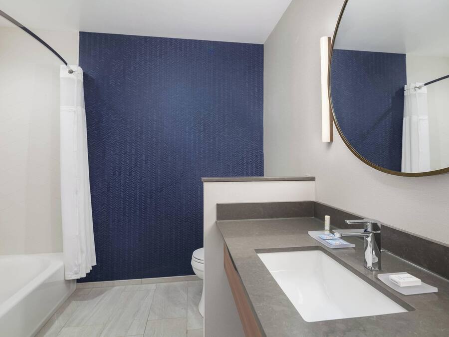 A modern bathroom with a bathtub, a sink with a mirror, and a toilet.