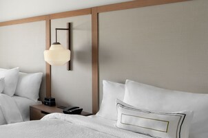 Habitación de hotel impecable con una cama, mesitas de noche, una lámpara y un teléfono.