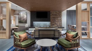 A modern living room with a stone accent wall, a flat-screen TV, and a round coffee table. - Fairfield Inn & Suites Kenosha Pleasant Prairie (Pleasant Prairie)