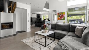 Een moderne woonkamer met een grijze hoekbank, een salontafel en een open haard.