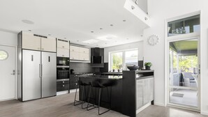 Een moderne keuken met een centraal eiland, barstoelen en een groot raam.