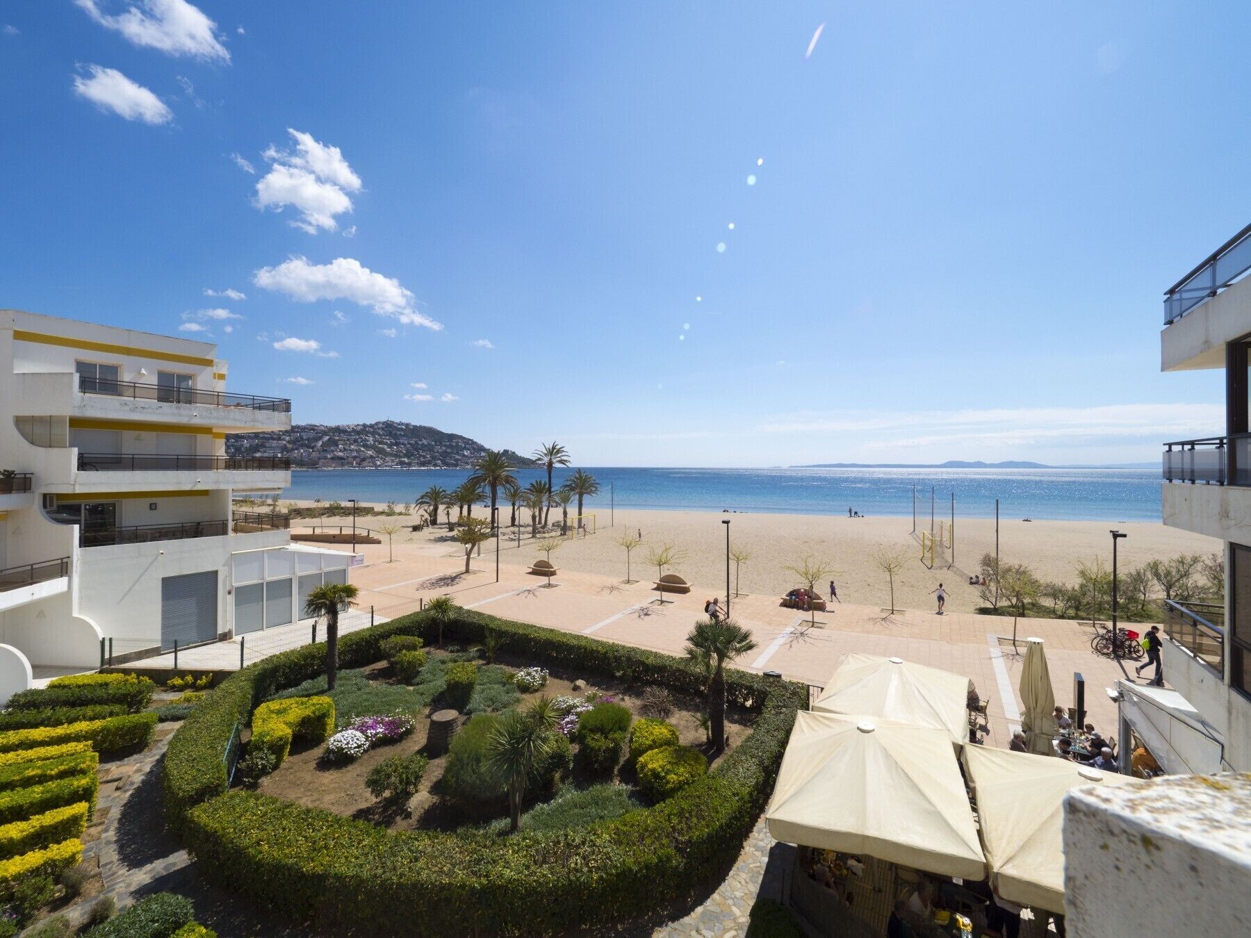 A beachfront hotel with a view of the sea, a landscaped garden, and a dining area with umbrellas.
