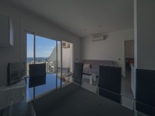 A modern hotel room with a balcony, a bed, a desk, and a TV. - Amazing apartment on the seafront in Roses Inmosantos Oasis B8 (Rosas / Roses)