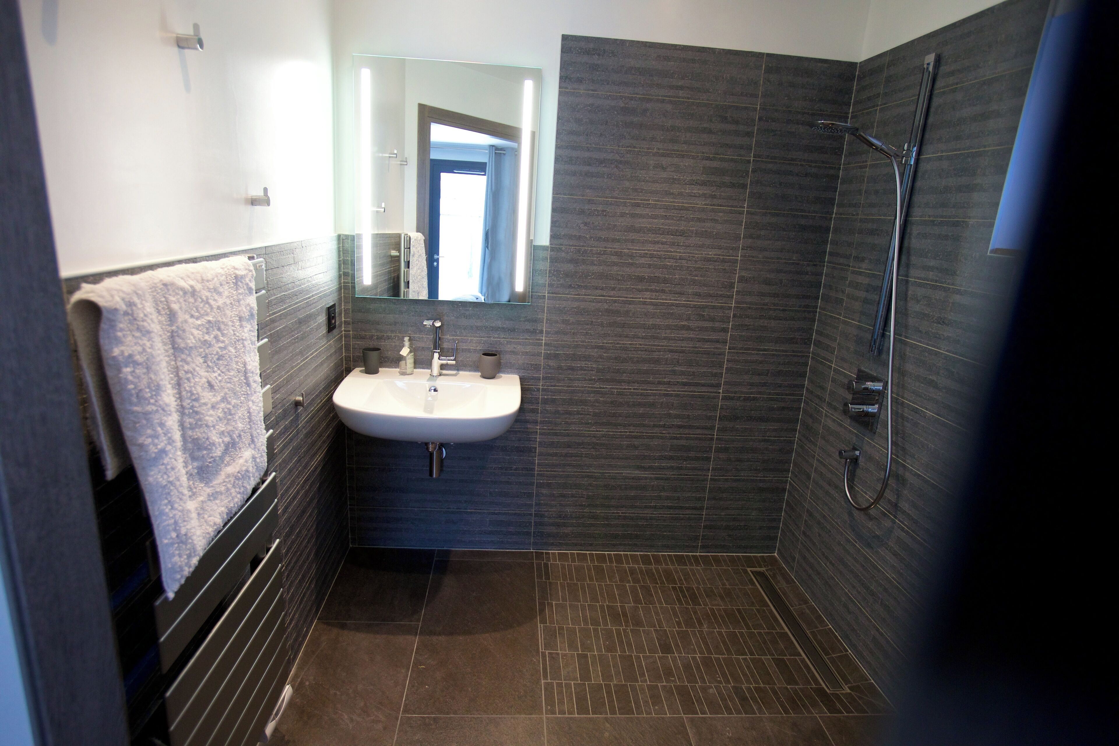 Une salle de bain moderne avec un lavabo, un miroir et une douche.