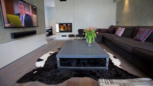 Una sala de estar moderna con una televisión de pantalla plana, una mesa de centro, un sofá y una chimenea.