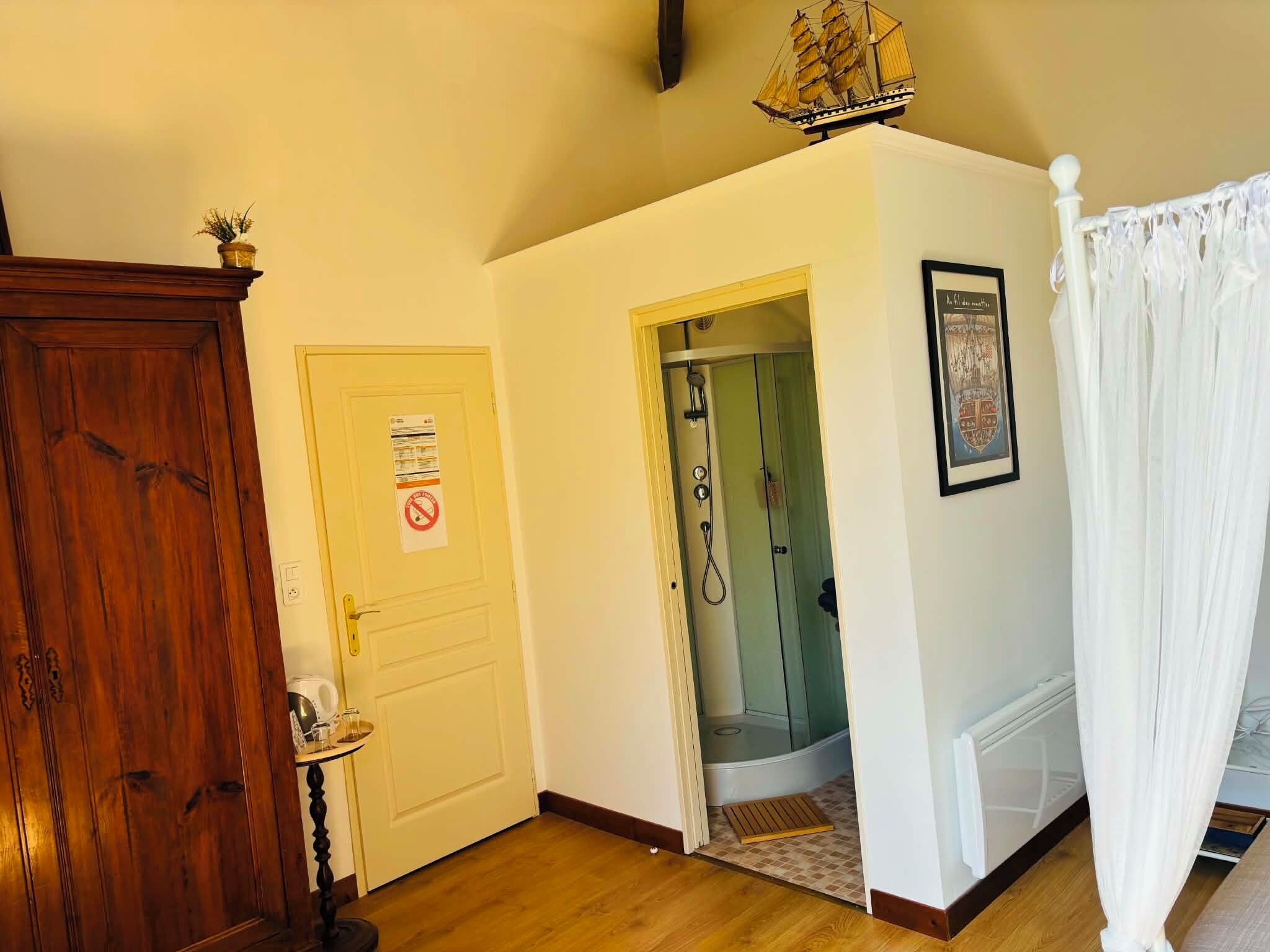 Una habitación con un armario de madera, una puerta con un cartel de prohibido fumar, una zona de ducha y un cuadro enmarcado en la pared.