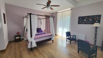 Une chambre à coucher avec un lit à baldaquin, un ventilateur de plafond, une chaise, un bureau et un tableau accroché au mur.