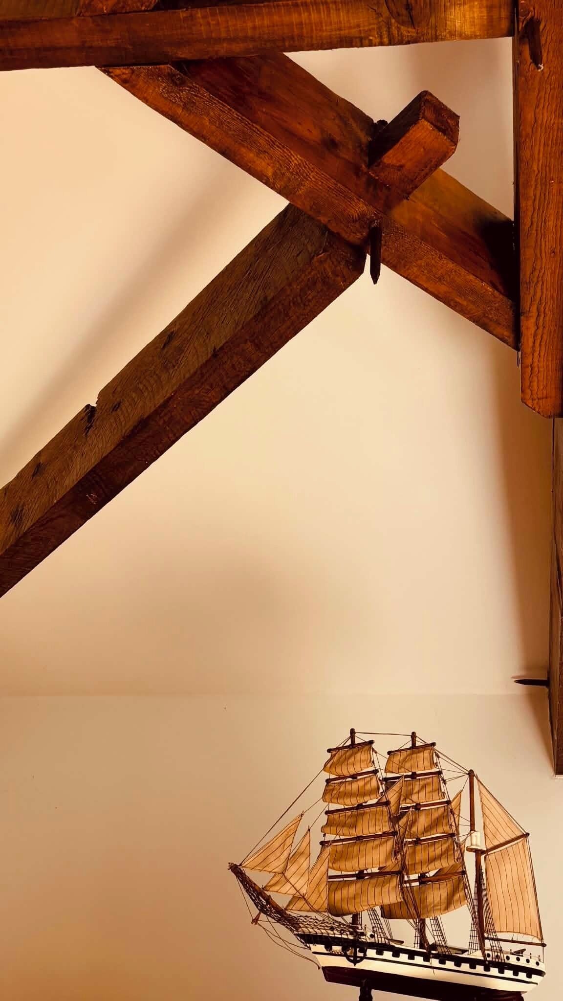 A model ship in a corner with wooden beams.