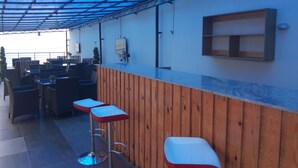 A bar area with wooden paneling and two red bar stools. - Orchid Suite & Apartment (Abuja)